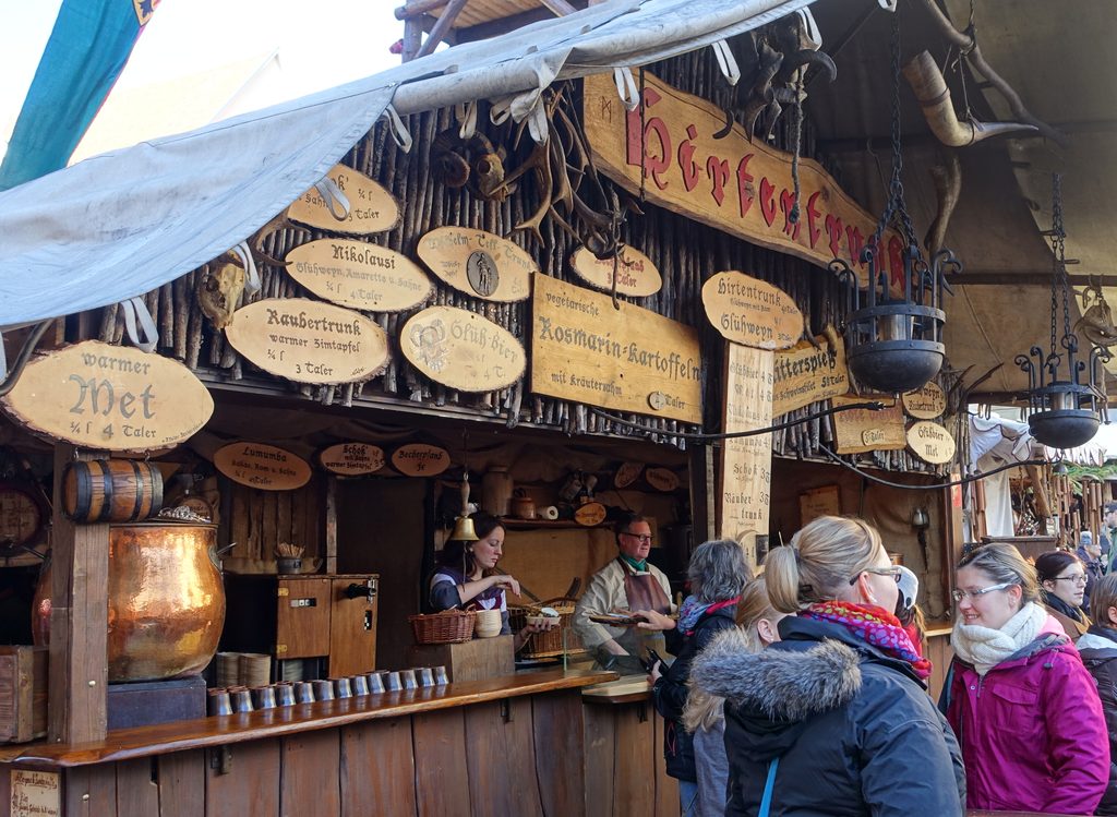 Marktstand mit Met und geschnitzten Holzschildern auf einem Mittelaltermarkt
