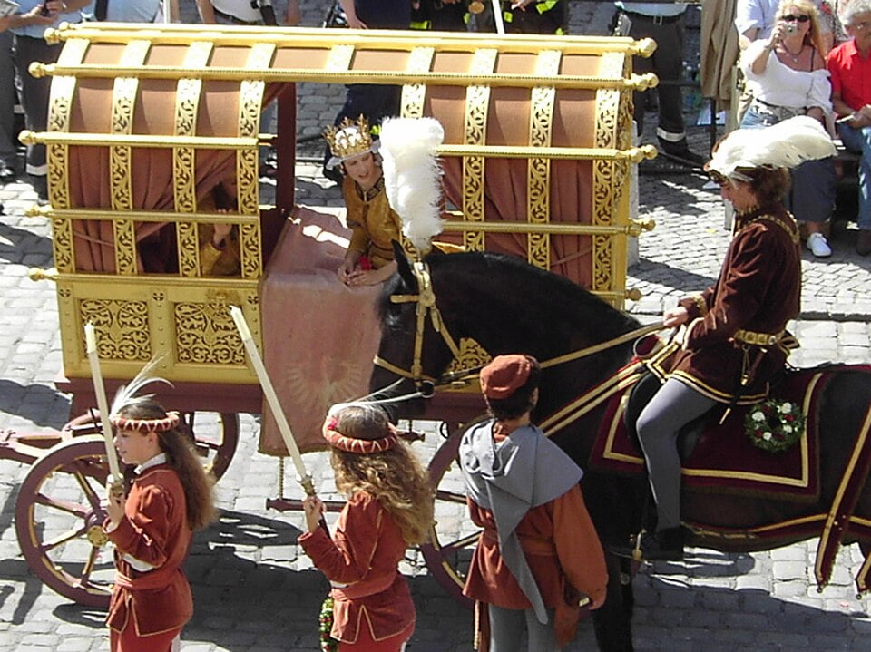 Goldene Brautkutsche mit Reiter in Renaissance-Gewand bei einem historischen Festumzug